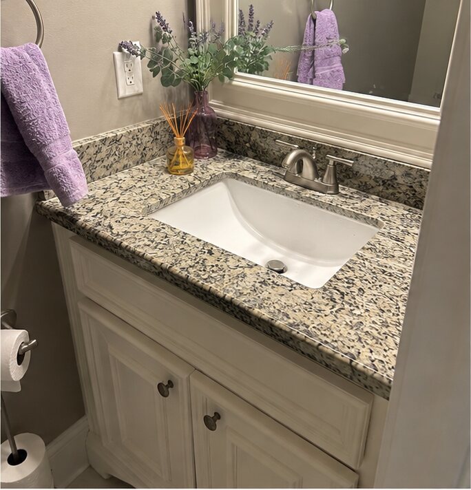 Powder bath vanity with a speckled granite top and backsplash