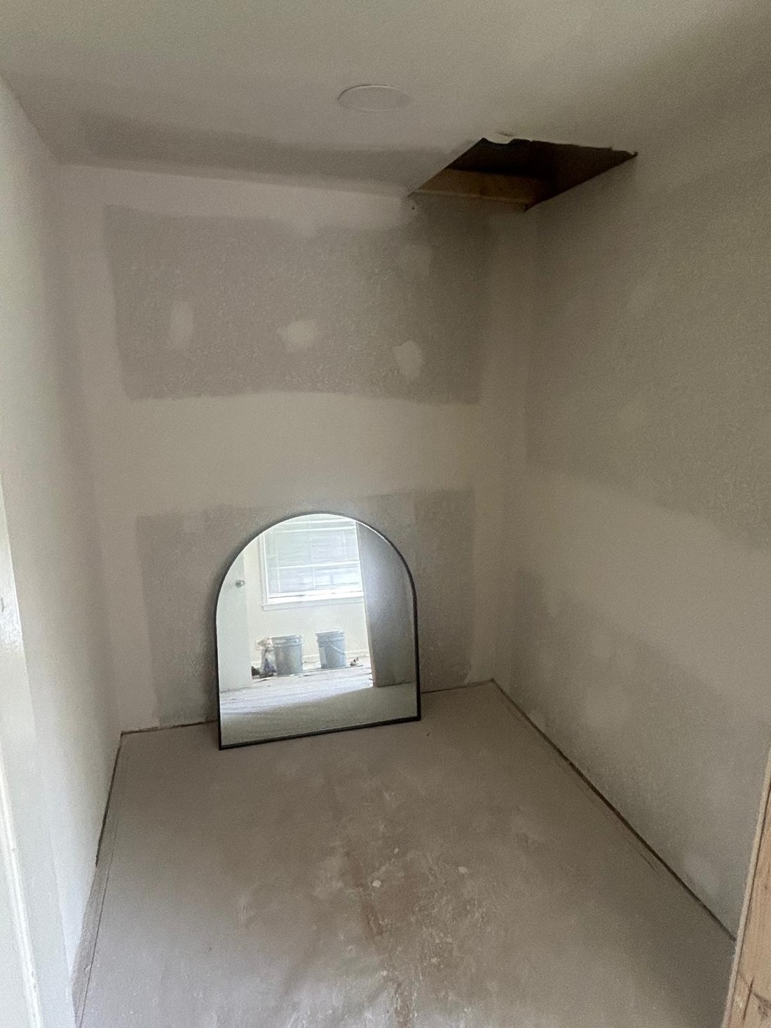 Leftover space with bare taped drywall, an open ceiling access hole and a bare slab floor