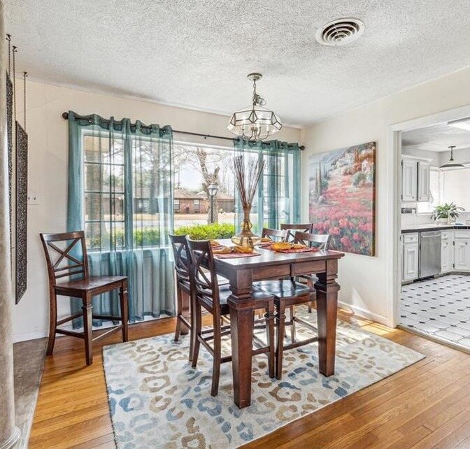 Dining area with a textured ceiling, teal curtains and worn wood floors