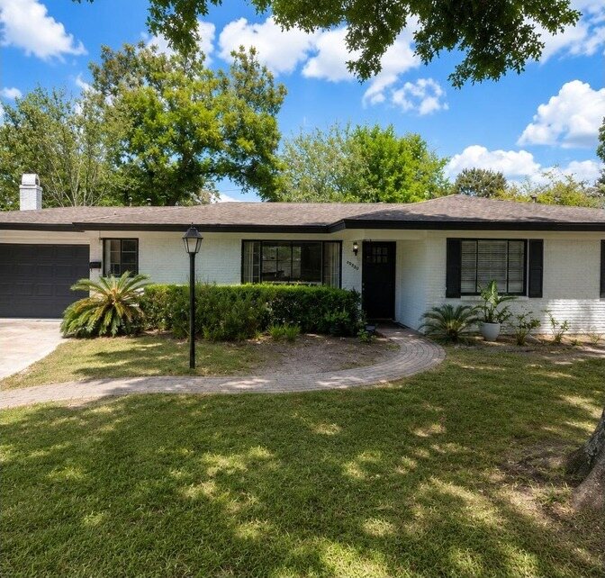 The same house in painted white brick with black trim and a black garage door