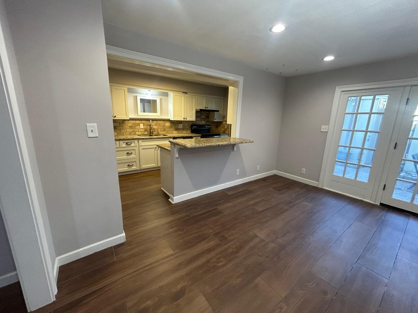 The same dining area with wood-look ceramic plank flooring running through to the kitchen