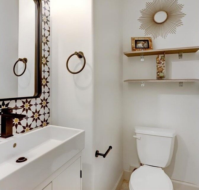 The same bath in white with a wallpaper panel, a trough sink and bronze fixtures