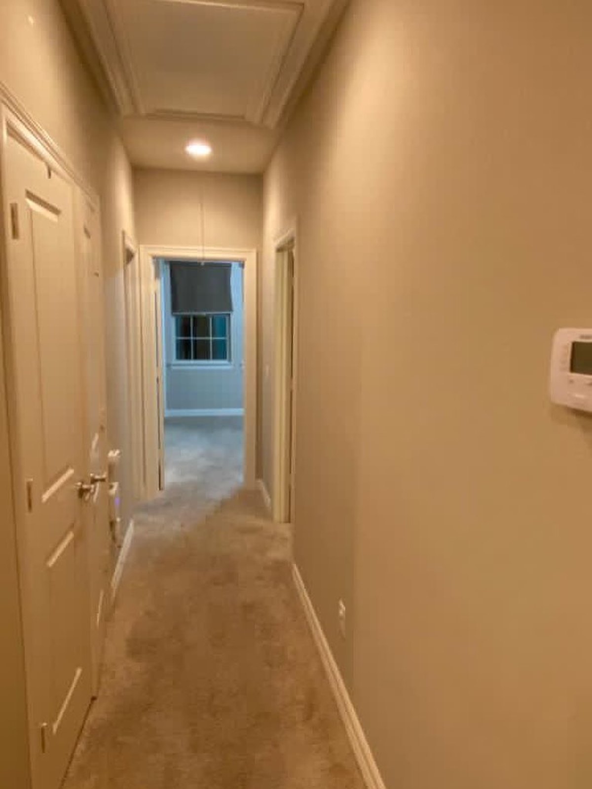 The same hallway in a lighter warm neutral with the doors and trim in white