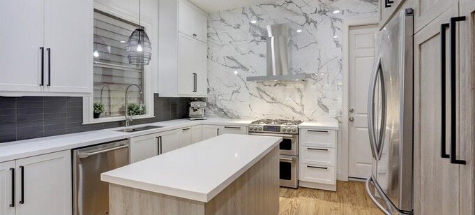 The kitchen with new white cabinets, quartz counters and a slab backsplash