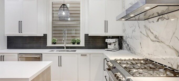 The finished kitchen from the range wall with the vent hood and slab backsplash