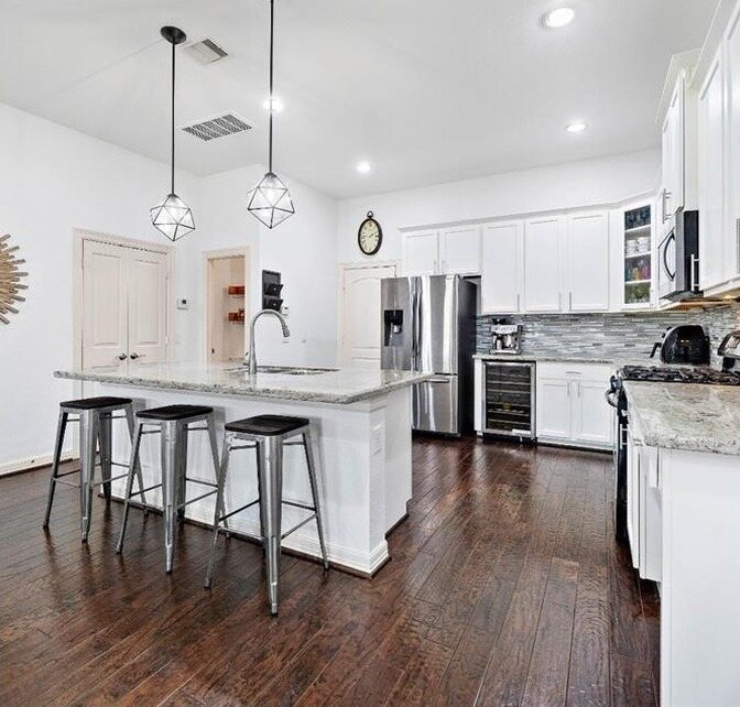 The same kitchen with white cabinets, white walls and new pendants