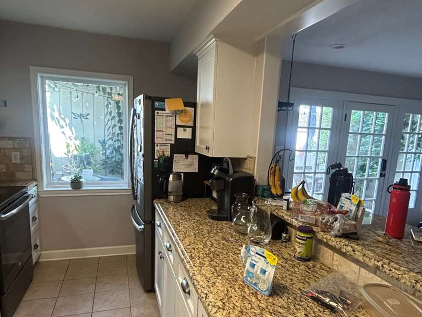 Kitchen seen from the dining opening with a beige granite peninsula and cream tile floor