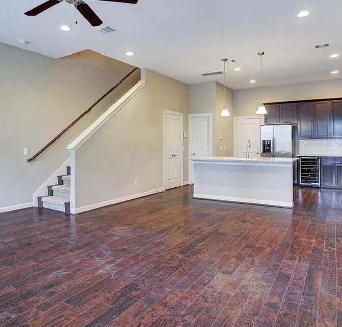 Open living room with beige walls and a dark stair rail