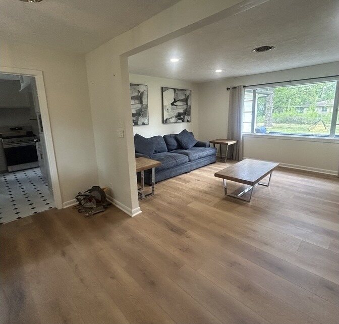 The same living room in white with new wide plank flooring and fresh trim