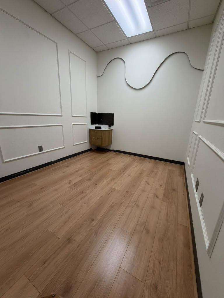 The same spa room with white applied wall paneling, a curved trim detail and new wood plank flooring