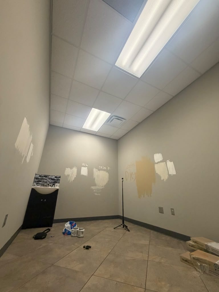 Spa treatment room in beige with paint samples on the wall, tile floor and a dated vanity